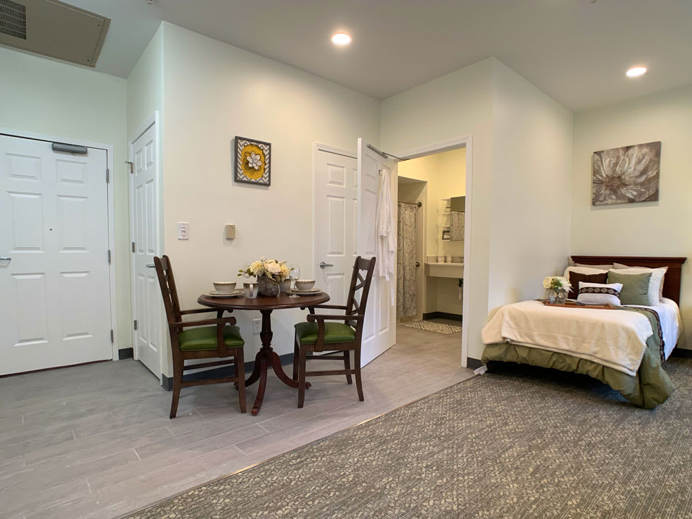 A cozy bedroom with an adjacent dining area, featuring a table set for two.