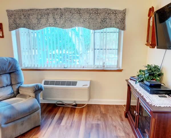 A cozy living room corner with a recliner, air conditioner, and decorative elements.