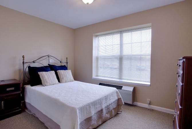 A minimalistic bedroom featuring a neatly made bed and a large window.