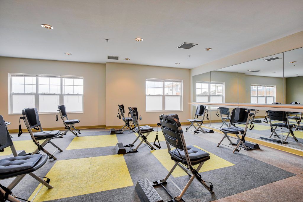 A spacious gym with exercise equipment and large windows allowing natural light.