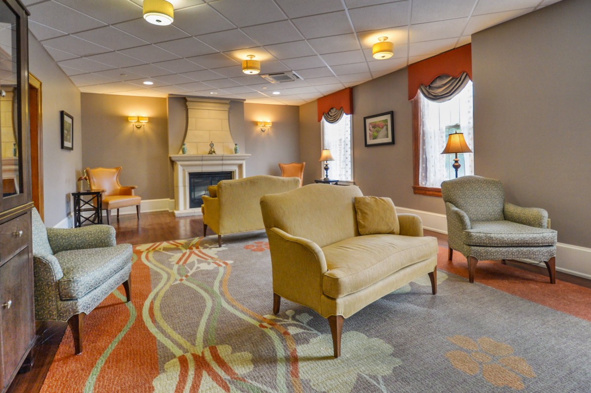 A cozy lounge with comfortable seating around a fireplace, featuring soft lighting and an elegant carpet.
