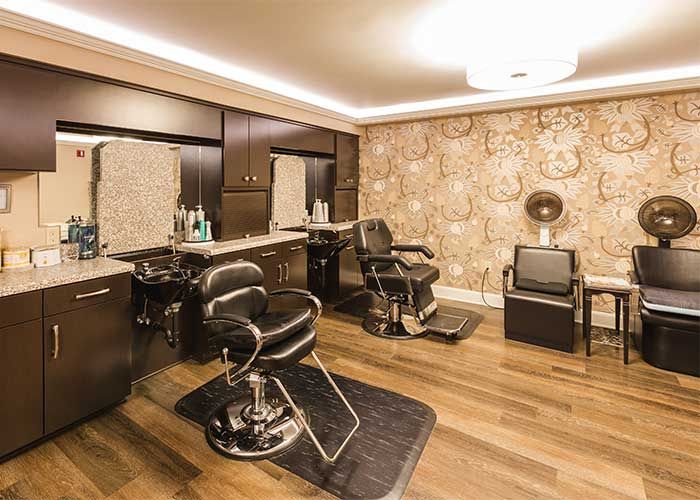 A stylish and modern barber shop interior with leather chairs and ornate wallpaper.