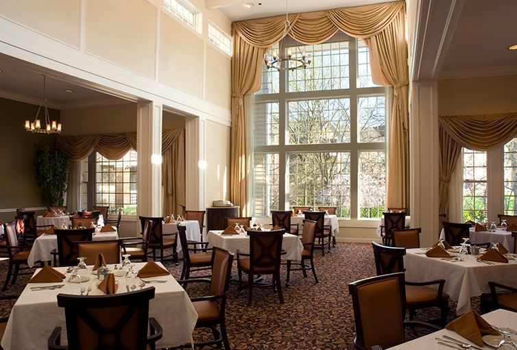A spacious restaurant dining room with elegant decor and large windows.