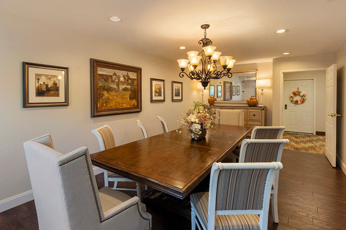 A beautifully decorated dining room with a wooden table, upholstered chairs, and an elegant chandelier.