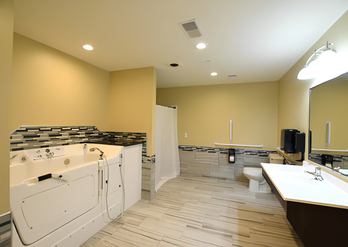 A spacious modern bathroom featuring a bathtub, shower, and toilet with tiled flooring.