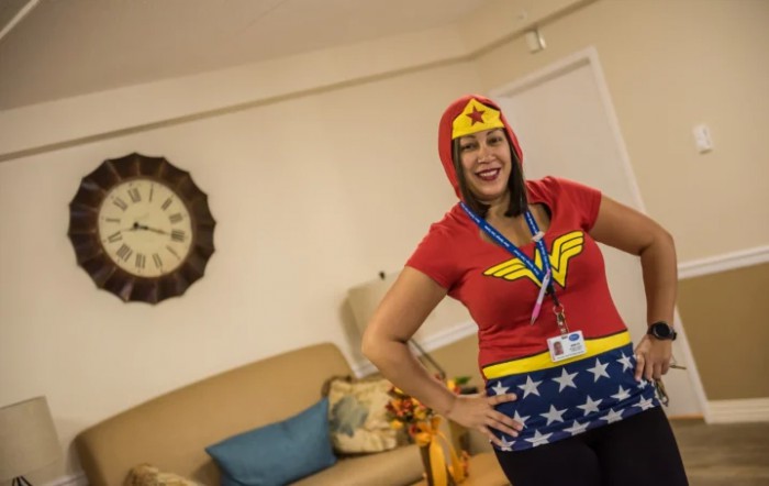 A woman dressed in a superhero costume poses in a living room.
