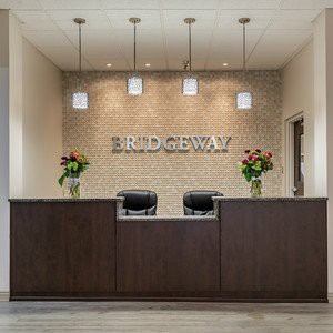 Modern reception area with a wooden desk and floral arrangements.
