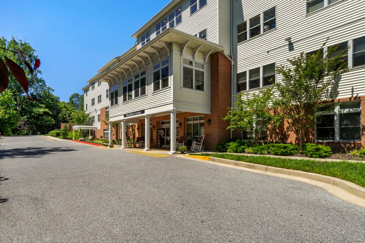 A multi-story residential building with a well-maintained exterior and surrounding greenery on a sunny day.