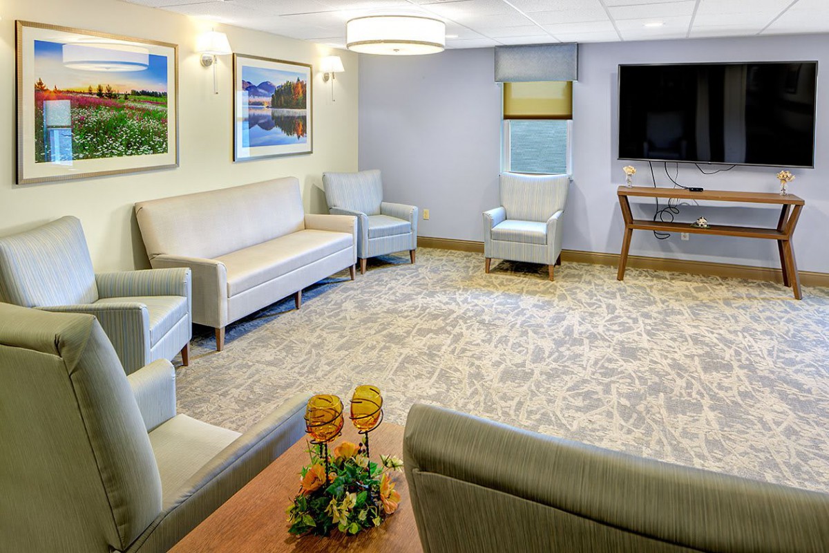 A comfortable waiting room with sofas, chairs, a television, and wall art.