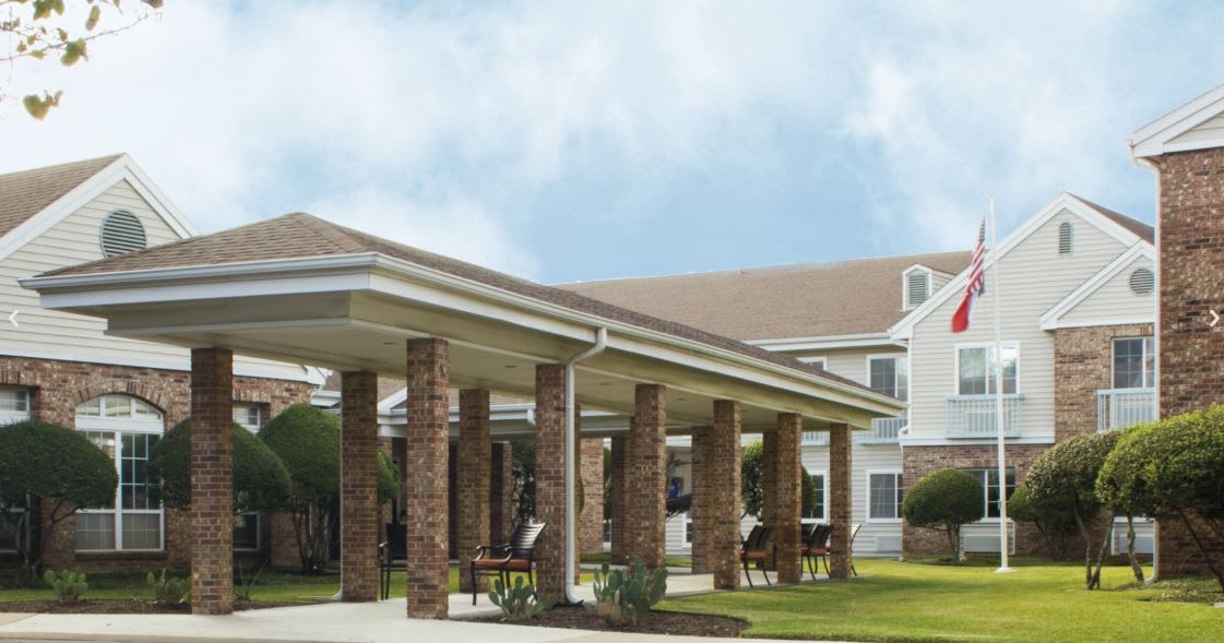 A large building with a covered porch supported by brick columns.