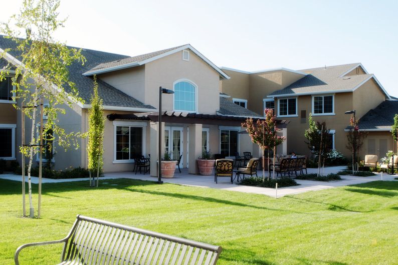 A modern residential building with a well-maintained lawn and outdoor seating area.
