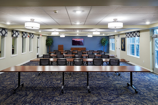 A spacious conference room set up for meetings, featuring tables and chairs arranged for group discussions.