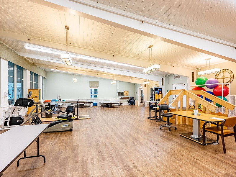 A spacious, open-plan office or workshop area with tables, chairs, and bright lighting.