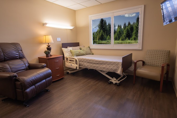 A well-furnished hospital room with a bed, chair, and a scenic view from the window.