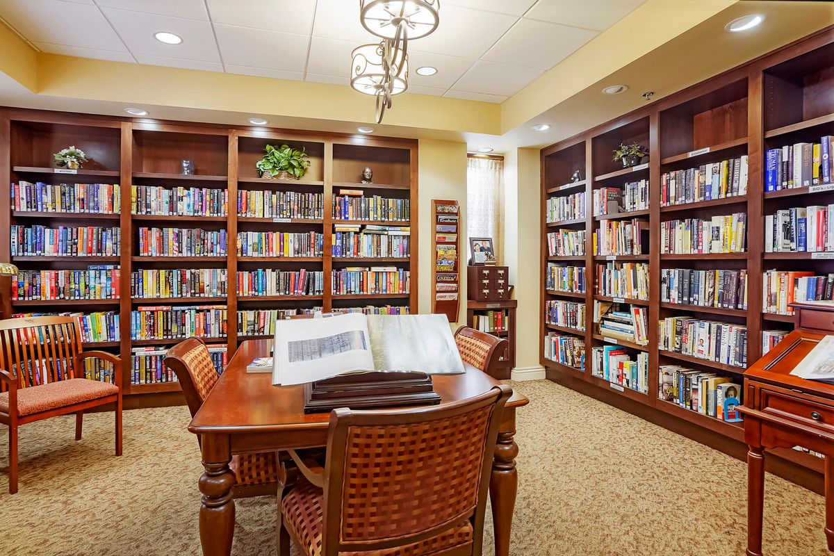 A cozy library reading room with wooden bookshelves and a table surrounded by chairs.