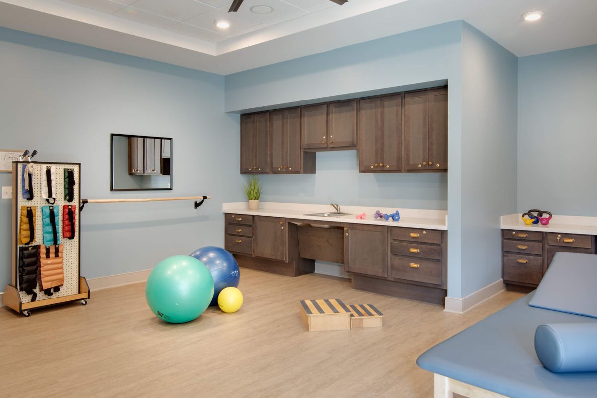A rehabilitation therapy room equipped with exercise balls, a mirror, and storage cabinets.