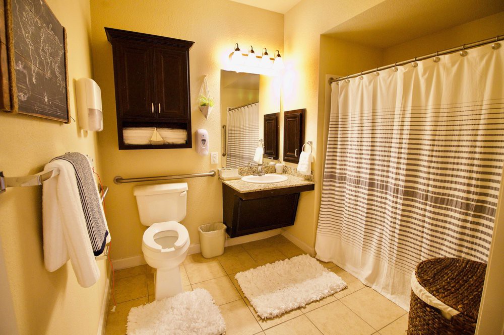 A modern bathroom with a toilet, sink, and shower area featuring a striped curtain.