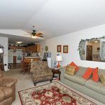 A cozy living room with a sofa, armchairs, and a patterned rug, connected to an open kitchen.