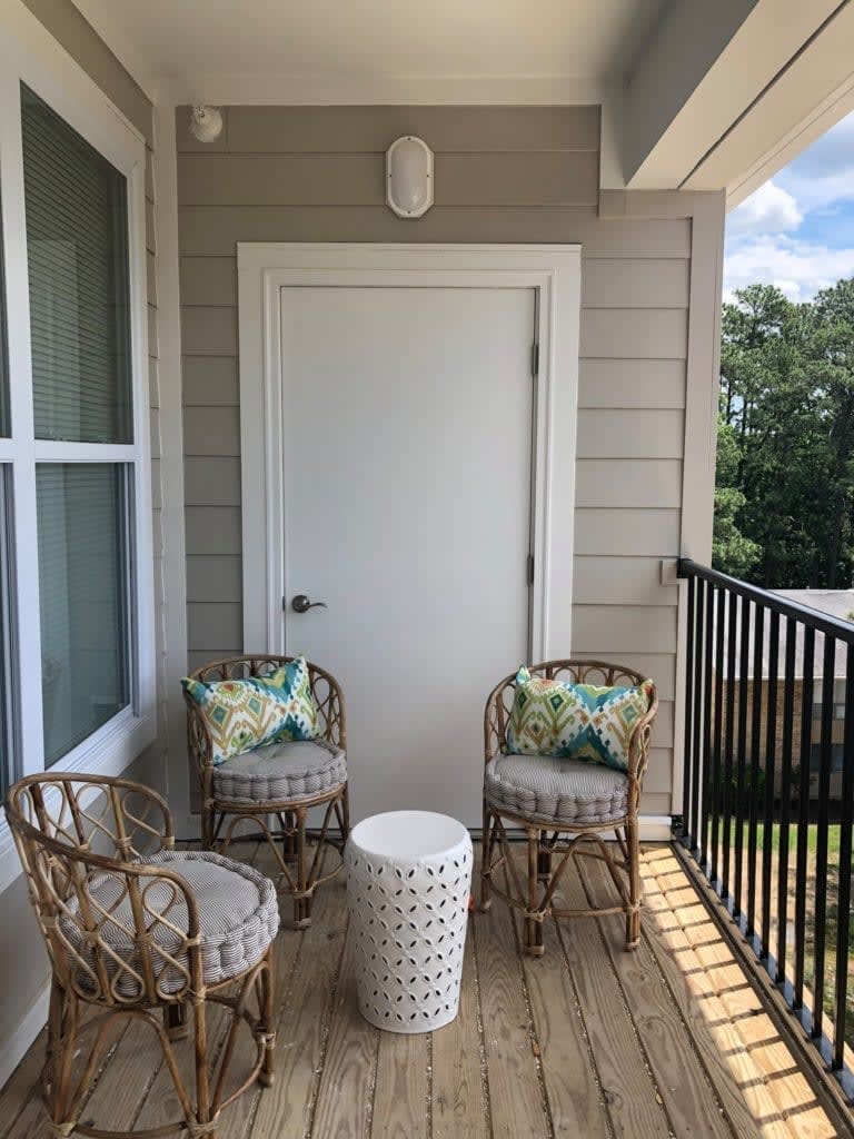 A cozy balcony setup with wicker chairs and a small table.