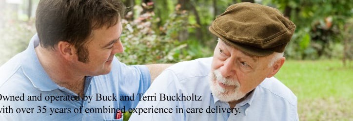A caregiver providing support and companionship to an elderly man outdoors.