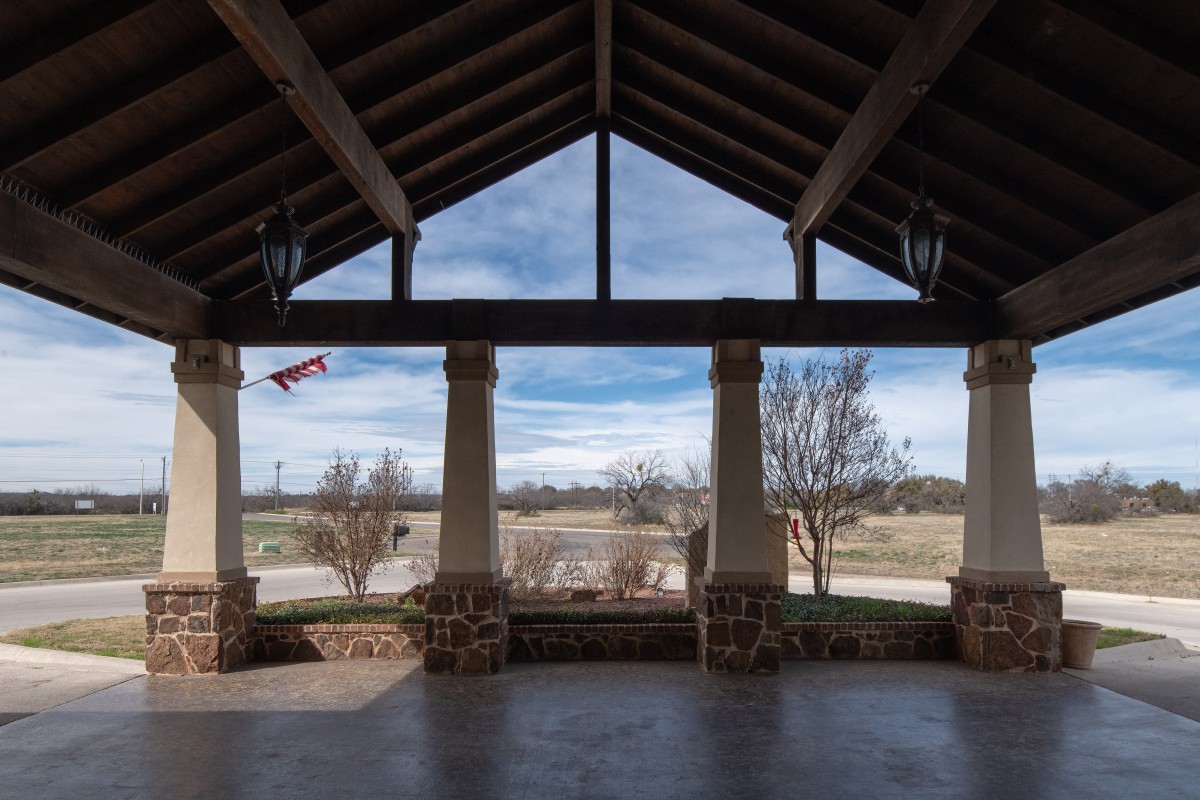 A scenic view from inside a pavilion with columns, overlooking a landscaped area.