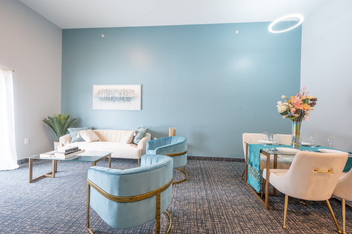 A modern living room with blue walls, featuring a comfortable sofa and stylish chairs.
