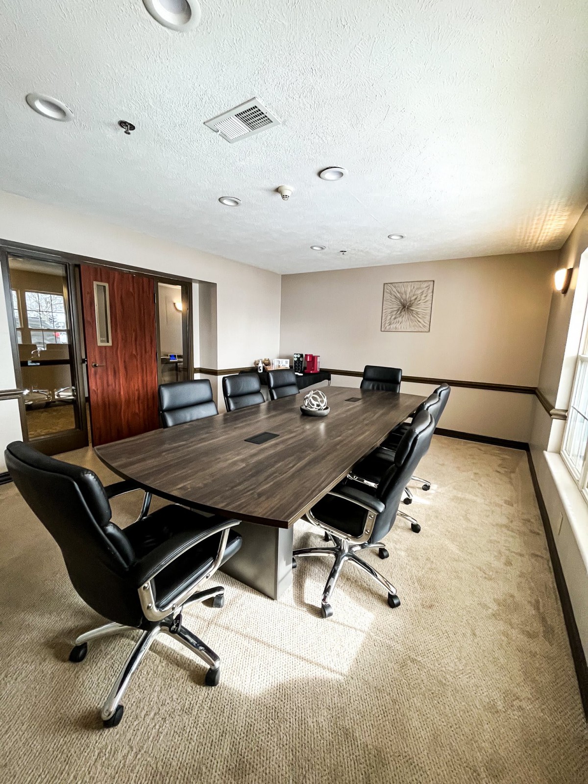 A modern conference room with a large meeting table and comfortable office chairs.