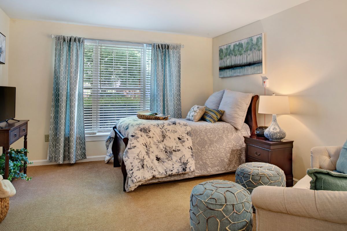 A cozy and elegantly decorated bedroom with a large window, featuring tasteful decor and comfortable furnishings.