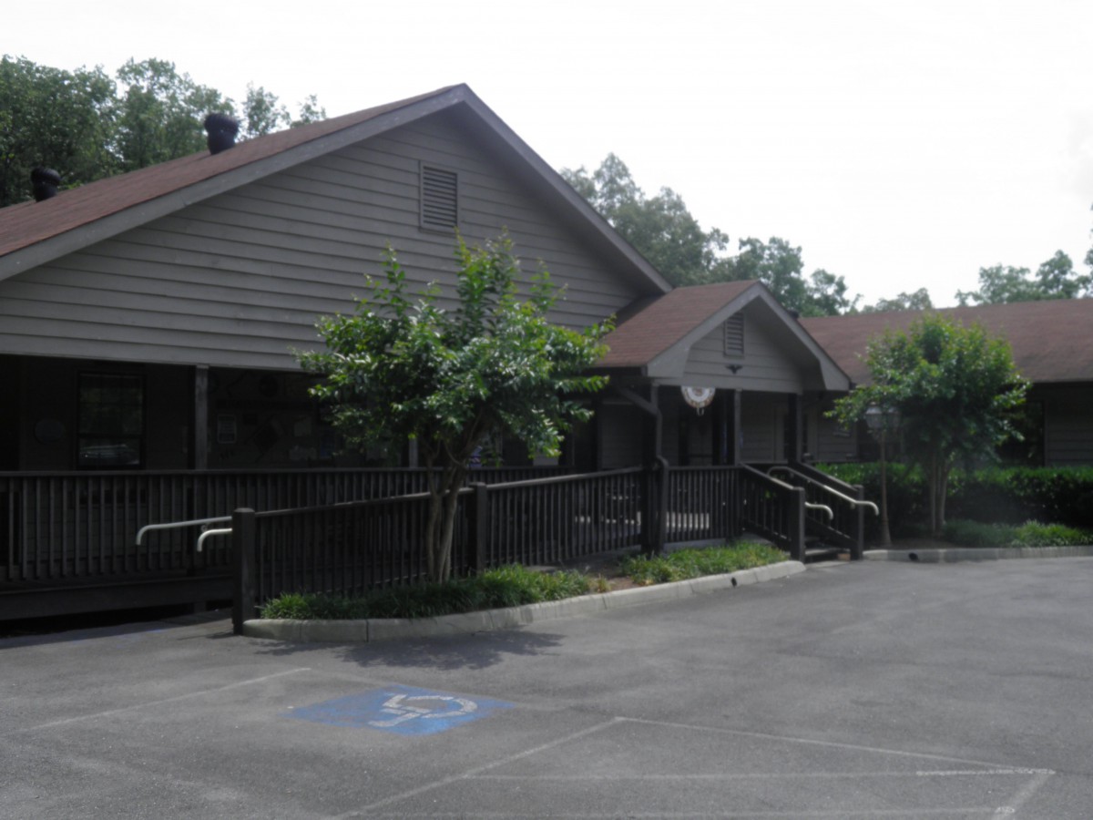 A view of a building with a parking lot and surrounding trees.