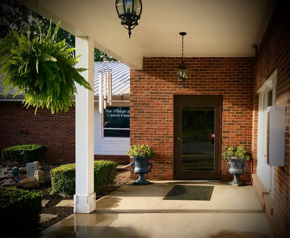 A brick building entrance with decorative plants and hanging lights.
