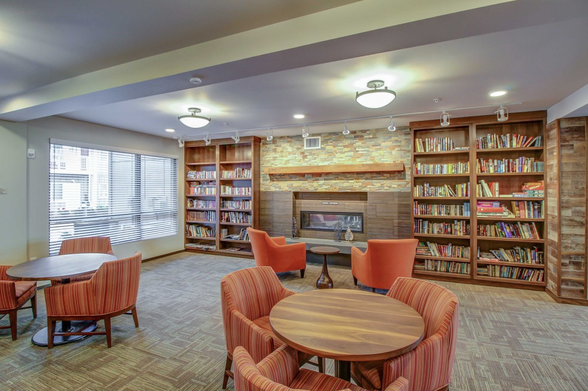A cozy library with bookshelves, a fireplace, and comfortable seating for reading.