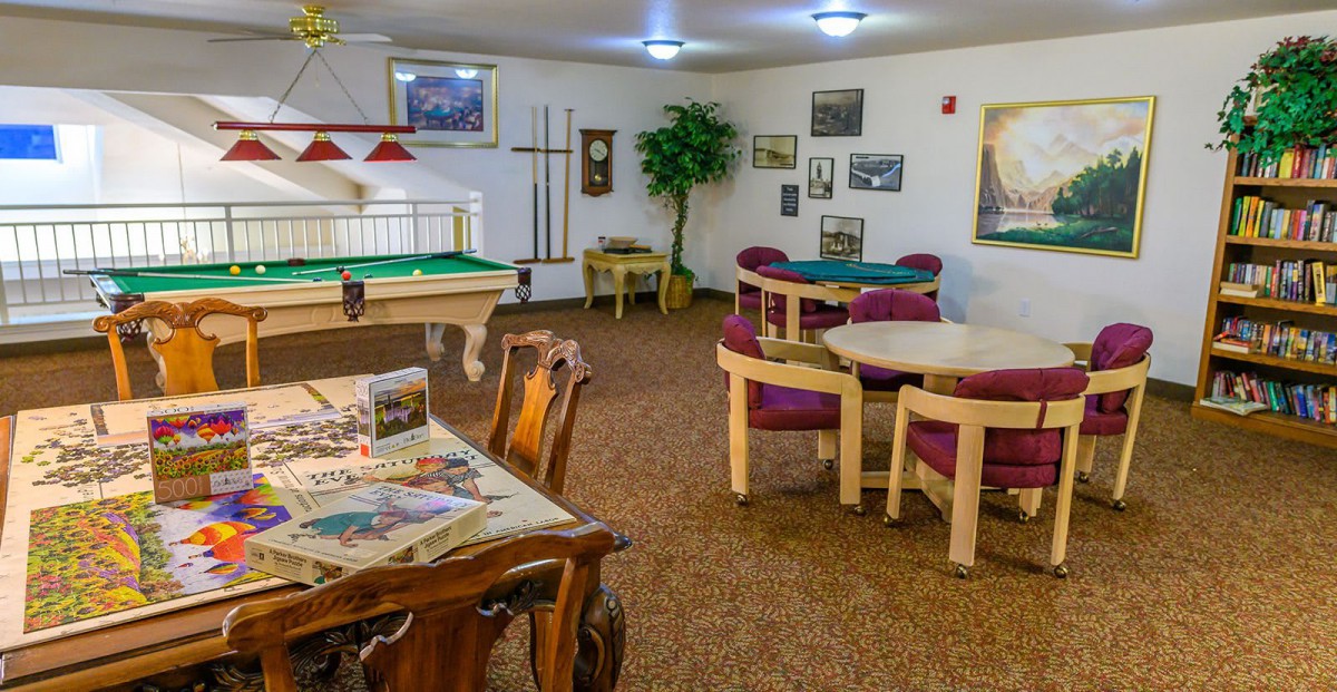 A game room featuring pool tables, chairs, and tables with various decorations.