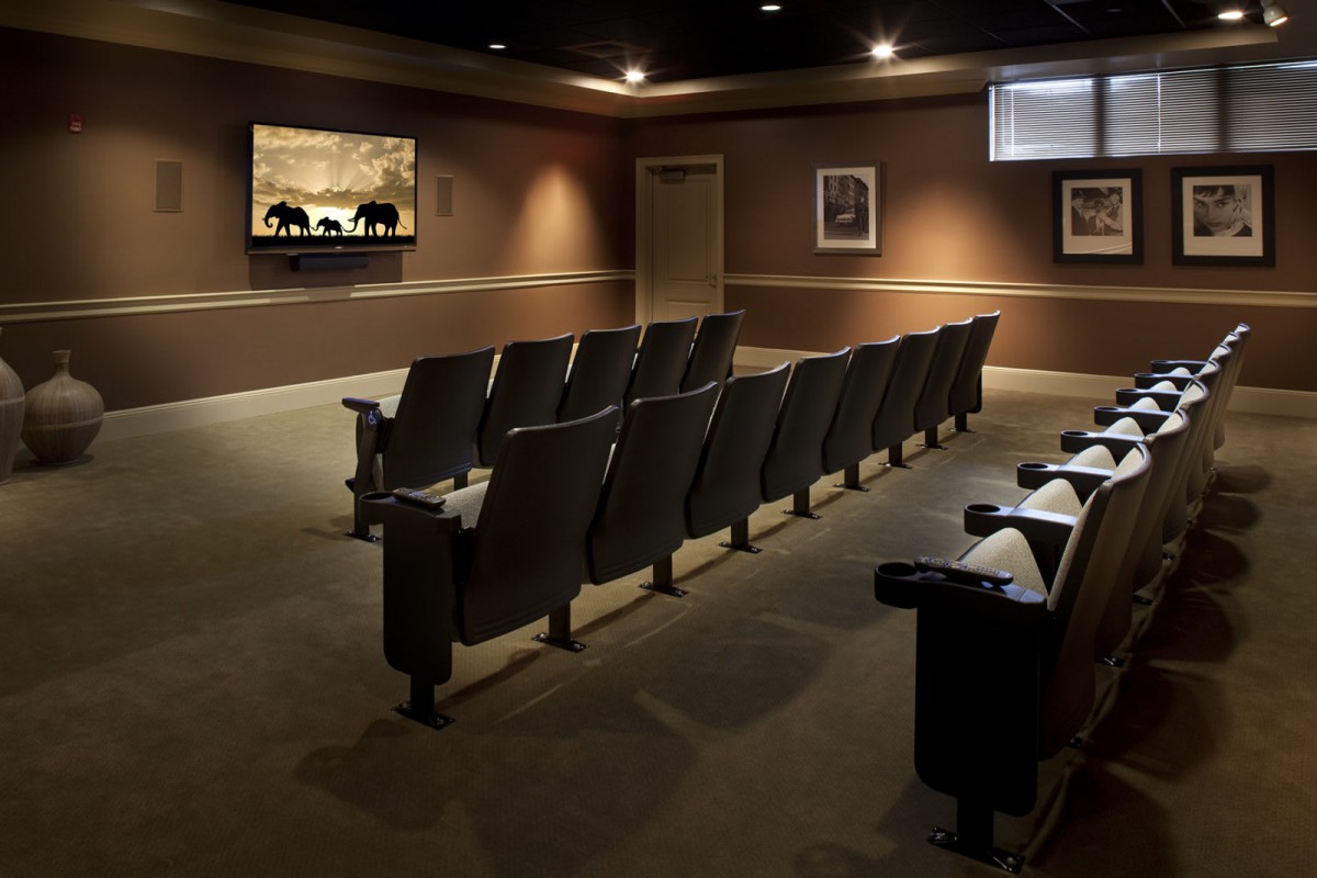 A cozy home theater setup with rows of comfortable seating and a large screen.