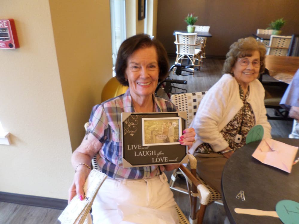 Two elderly women smiling and celebrating indoors.