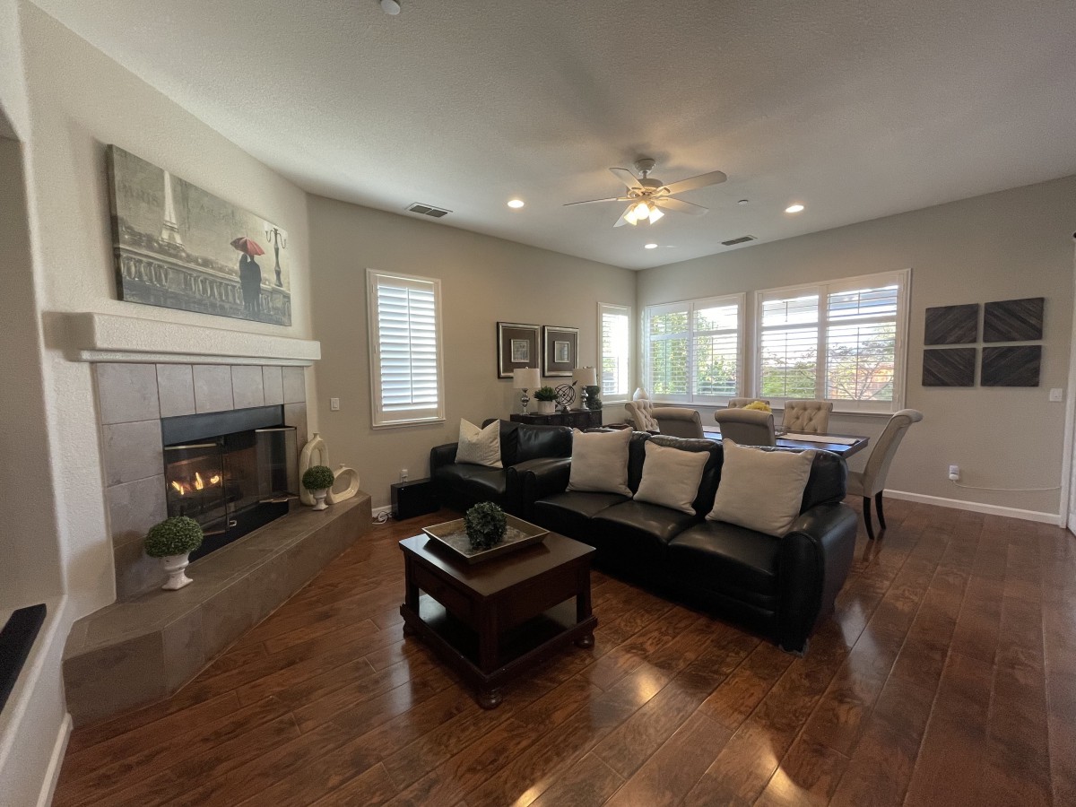 A cozy living room with a large sofa, fireplace, and wooden flooring.