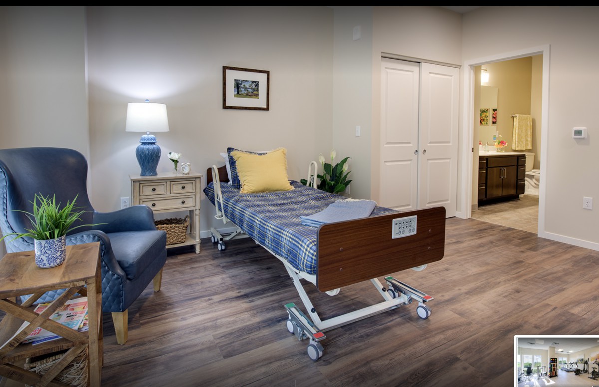 A well-furnished hospital room with a bed, lamp, and cozy decor.