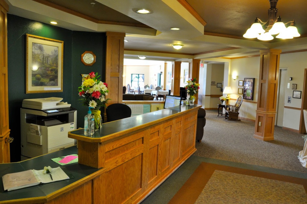 A well-lit lobby with a wooden reception desk adorned with vases of flowers.