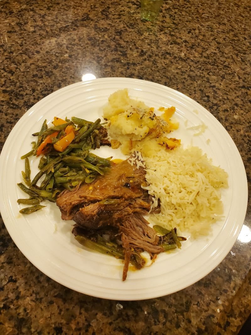 A delicious dinner plate featuring meat, rice, and mixed vegetables.