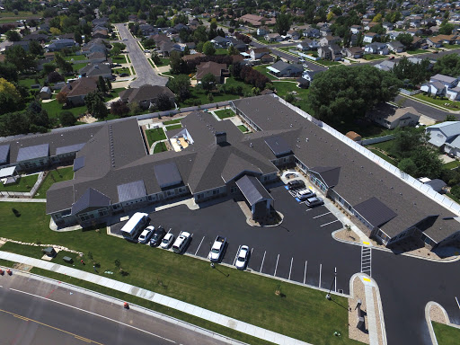 Aerial view of a modern building surrounded by a parking lot and residential neighborhood.