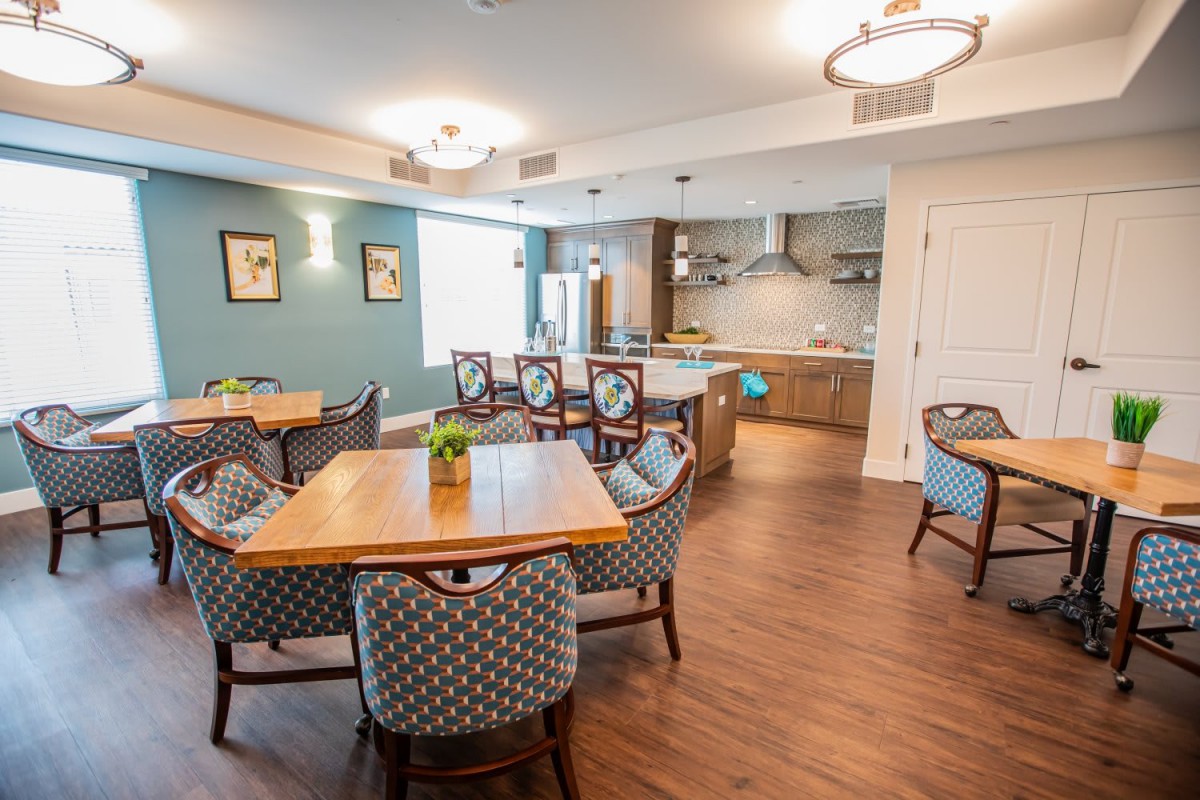 A modern and cozy dining area with a connected kitchen, featuring elegant furniture and bright lighting.