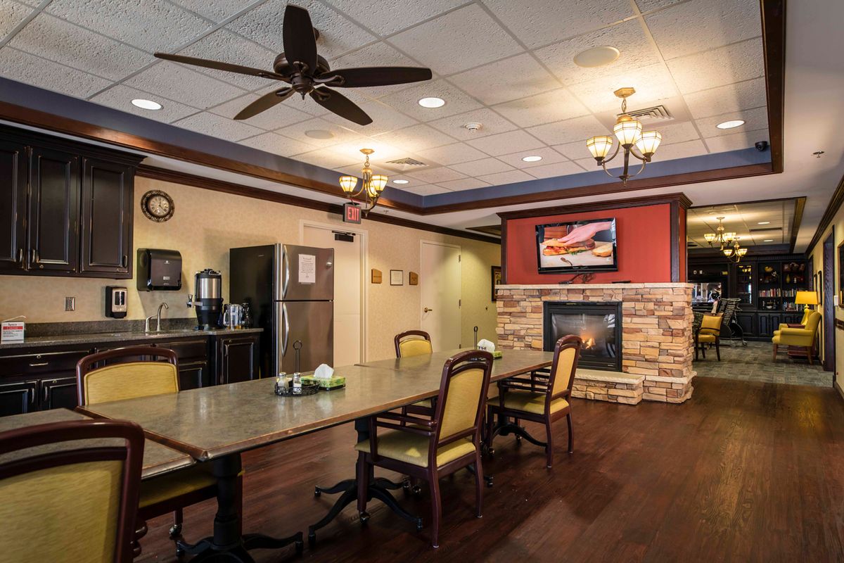 A cozy kitchen and dining area featuring a large table, chairs, a stone fireplace, and modern appliances.