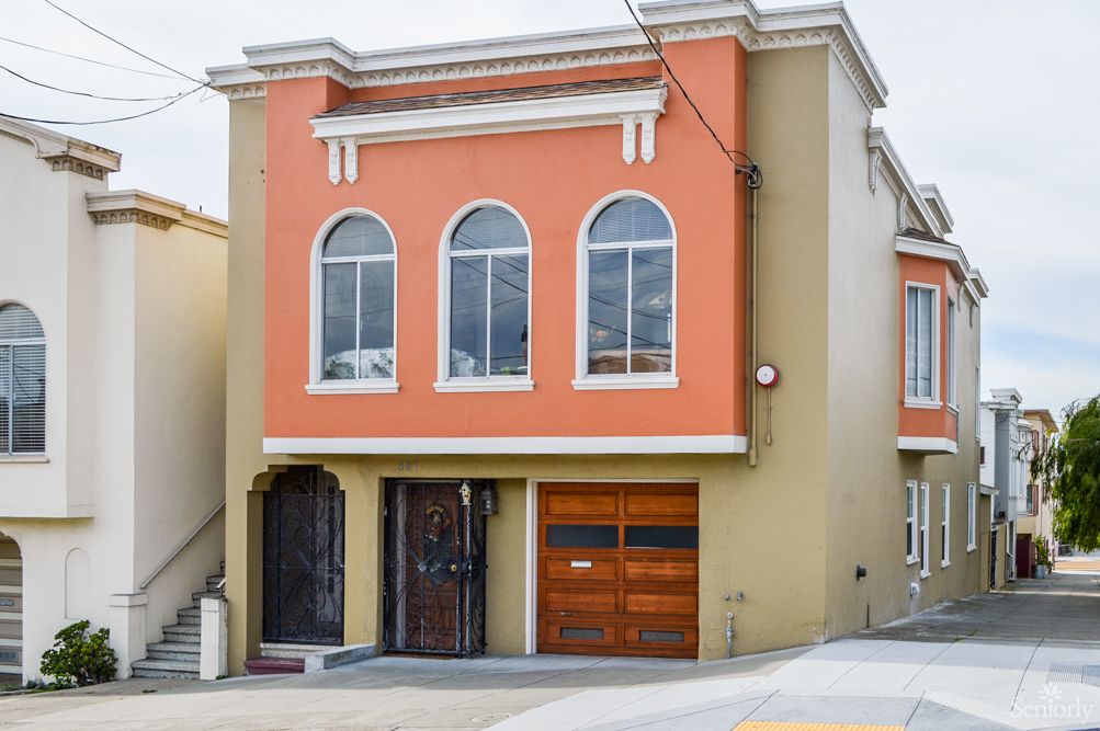 A two-story house with an orange exterior and arched windows, featuring a garage door.
