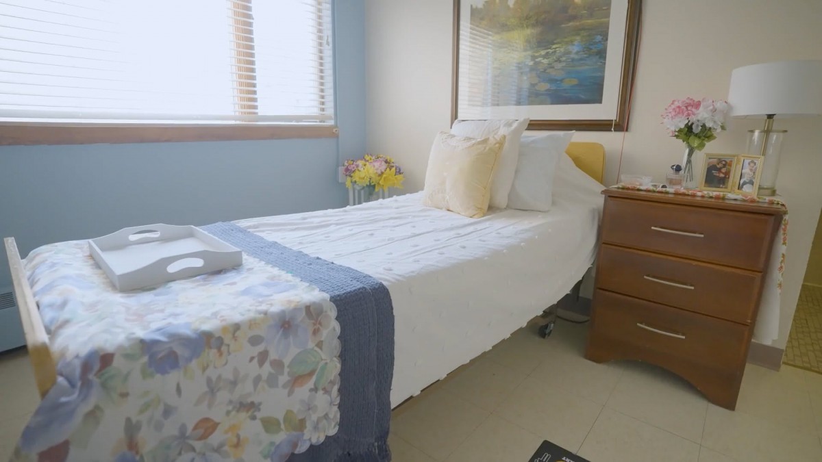 A cozy bedroom featuring a neatly made single bed with decorative pillows and a floral runner.