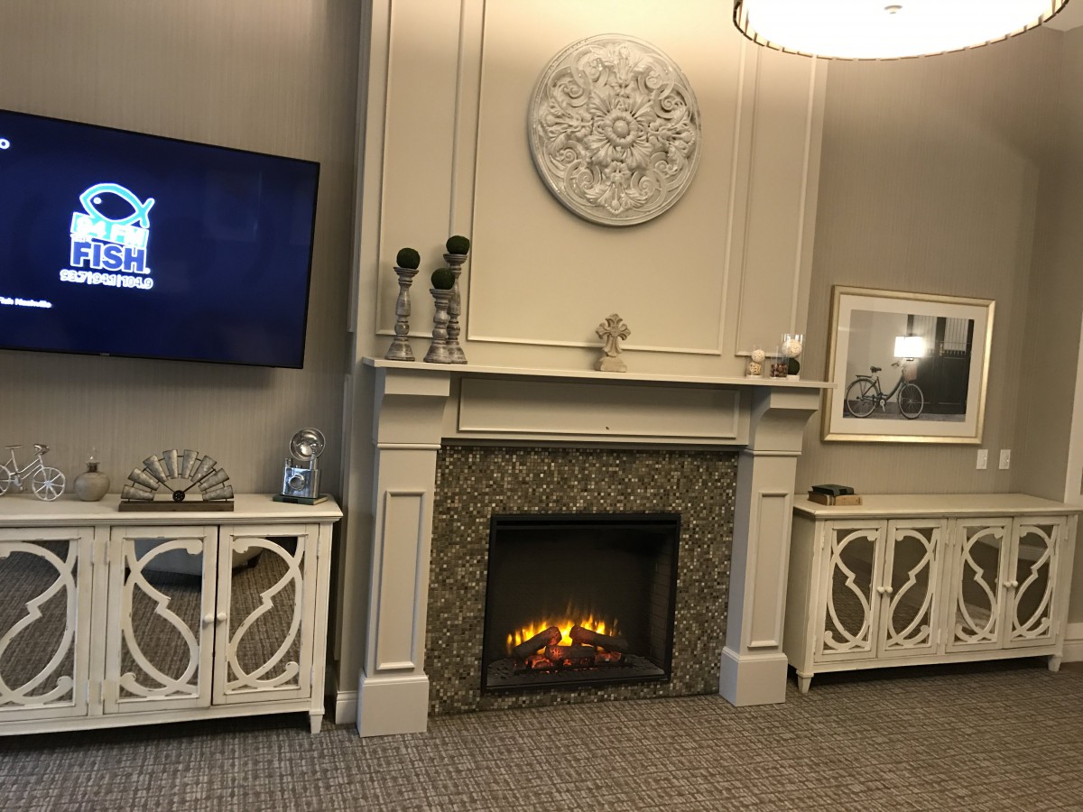 A cozy living room featuring a lit fireplace, wall-mounted television, and elegant decor.