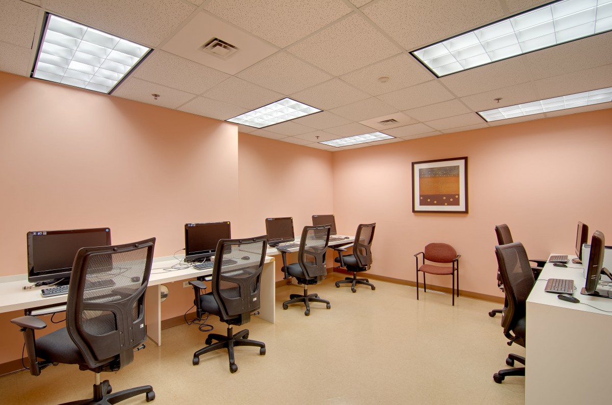 A computer lab with multiple workstations and office chairs in a well-lit room.