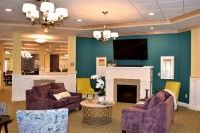 A cozy living room with comfortable seating, a fireplace, and a television mounted on the wall.