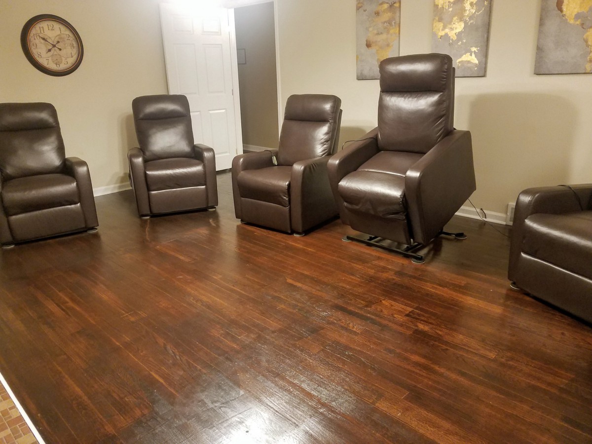 A cozy living room setup featuring four leather recliner chairs on a polished wooden floor.
