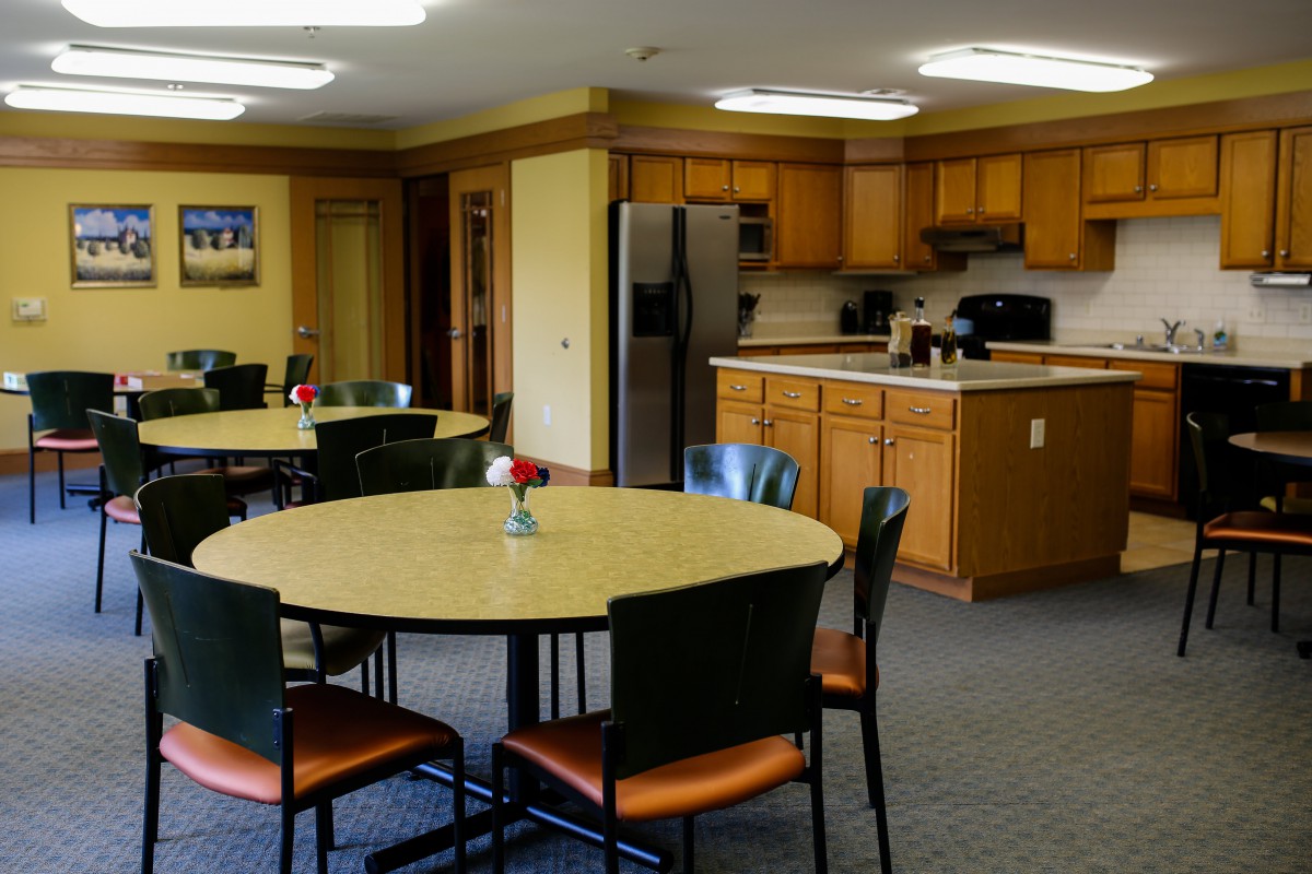 A communal kitchen and dining area with tables, chairs, and appliances.