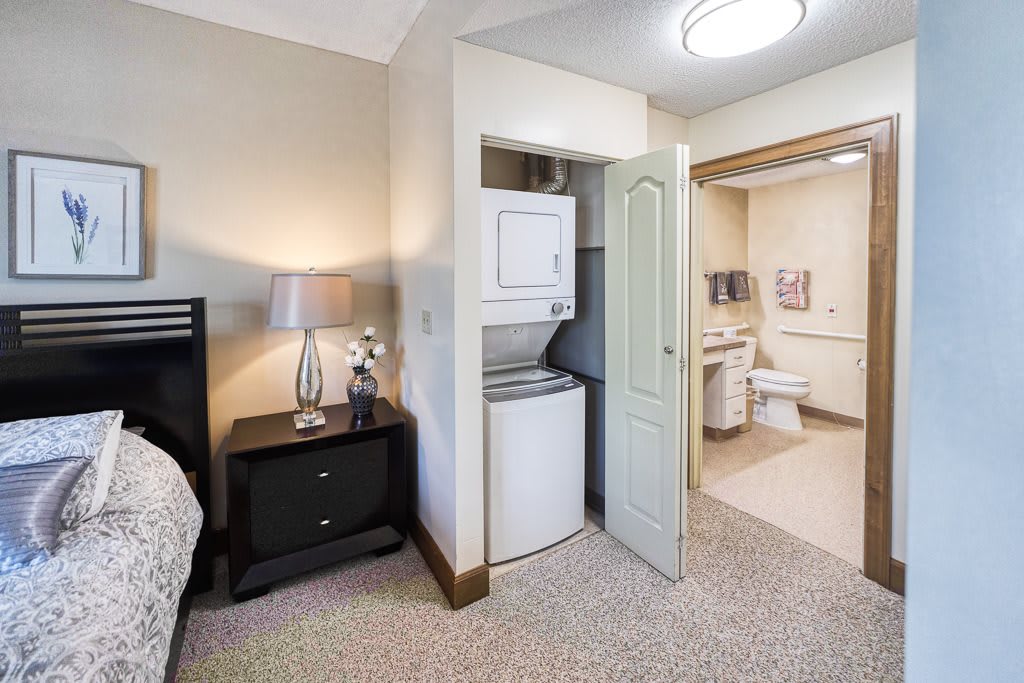 A cozy bedroom with an adjacent laundry area and bathroom.