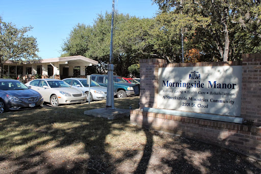 Entrance of a healthcare facility with parked cars and a prominent sign.